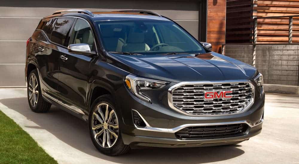 A black 2020 GMC Terrain is parked in a driveway in front of a metal garage door. 