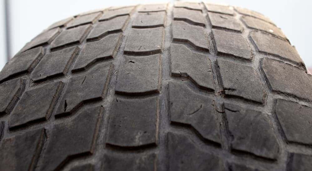 A close up of a tire with low tread, which is when you should bring your car to a local tire shop, is shown.