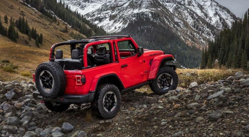 A red 2018 Jeep Wrangler is parked off-road with a mountain view.