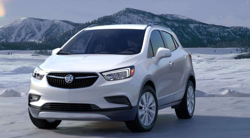 A white 2020 Buick Encore is parked on a snowy flat with snow covered mountains in the distance. 