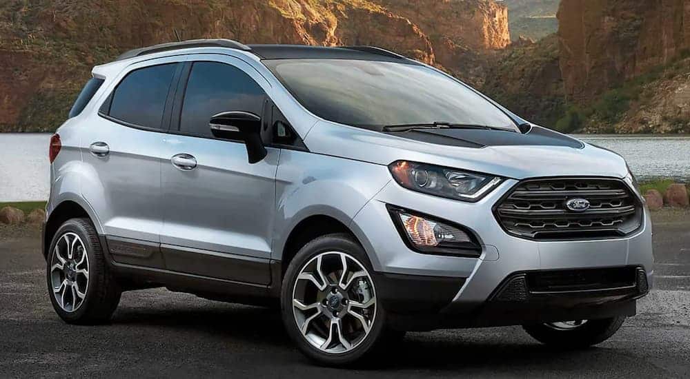 A silver and black 2020 Ford Ecosport is parked in an empty parking lot with mountains in the background.