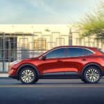 A red 2020 Ford Escape is driving past a white building.