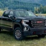 A black 2020 GMC Sierra AT4 is parked on grass next to a small lake.
