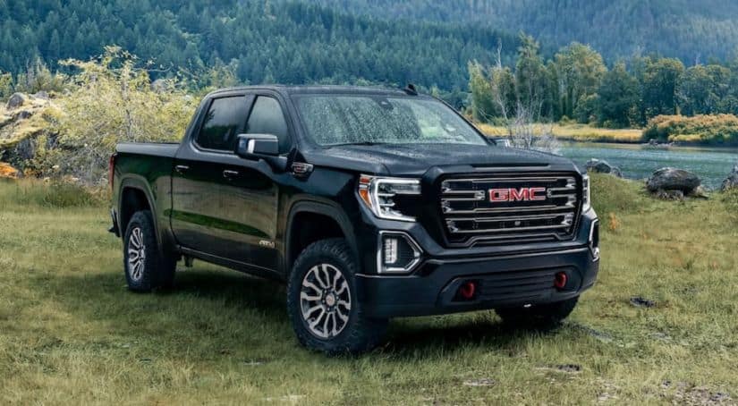 A black 2020 GMC Sierra AT4 is parked on grass next to a small lake.