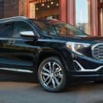 A black 2020 GMC Terrain is parked next to a lit up store front.