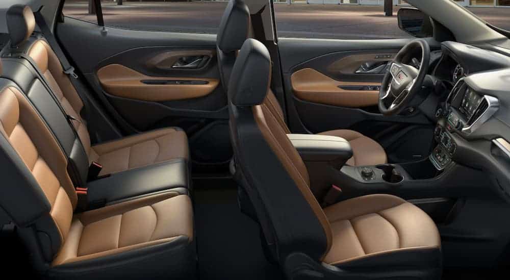 A side view of the front and rear black and brown leather interior of a 2020 GMC Terrain, which wins when comparing the 2020 GMC Terrain vs the 2020 Honda CR-V, is shown.