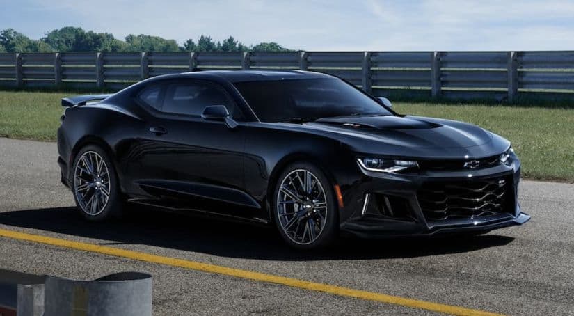 A black 2021 Chevy Camaro is parked on the race track after winning the 2021 Chevy Camaro vs 2021 Ford Mustang performance showndown.