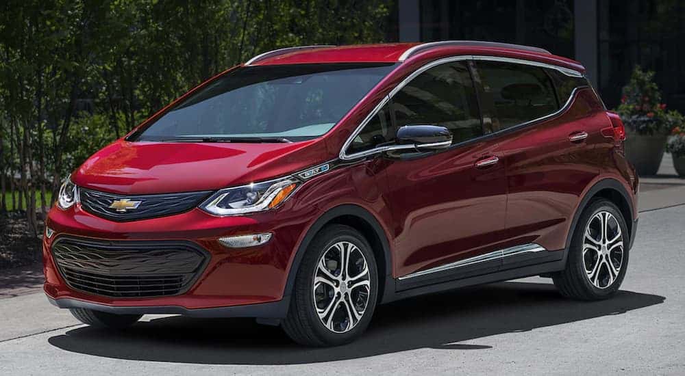 A red 2020 Chevy Bolt EV, which is a popular option at a Chevy dealer near me, is parked in a driveway. 