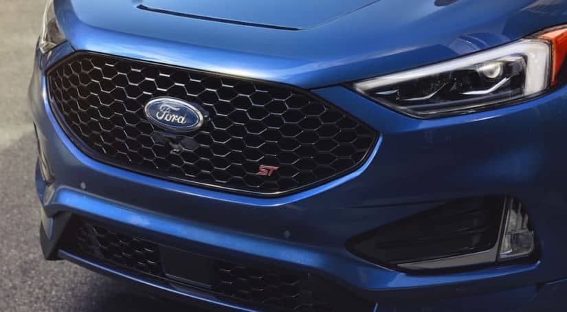 A close up of the blue Ford logo is on a Ford SUV's black grille.