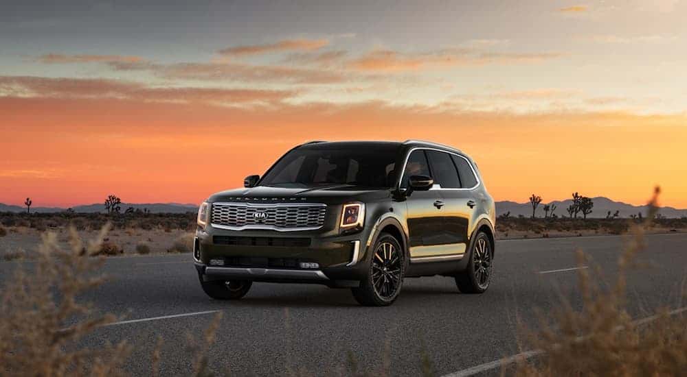 A dark green 2020 Kia Telluride, which is a popular option among Pennsylvania auto dealers, is parked on a road while the sun sets behind it. 