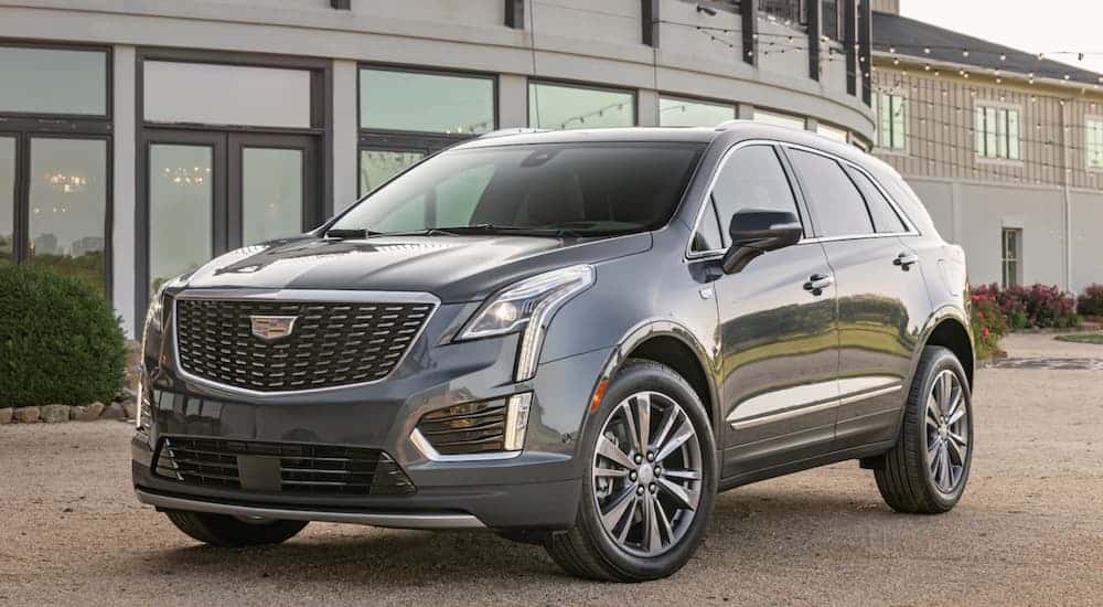A grey 2020 Cadillac XT5 is parked in front of a glass building. 