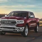 A red 2020 Ram 1500, which is popular among Ram trucks, is driving on a highway before sundown.