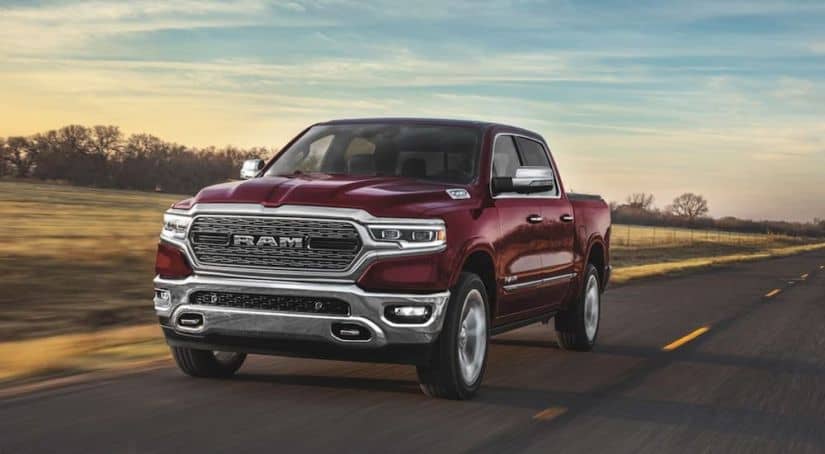 A red 2020 Ram 1500, which is popular among Ram trucks, is driving on a highway before sundown.