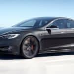 A black 2021 Tesla Model S is driving across a bridge.