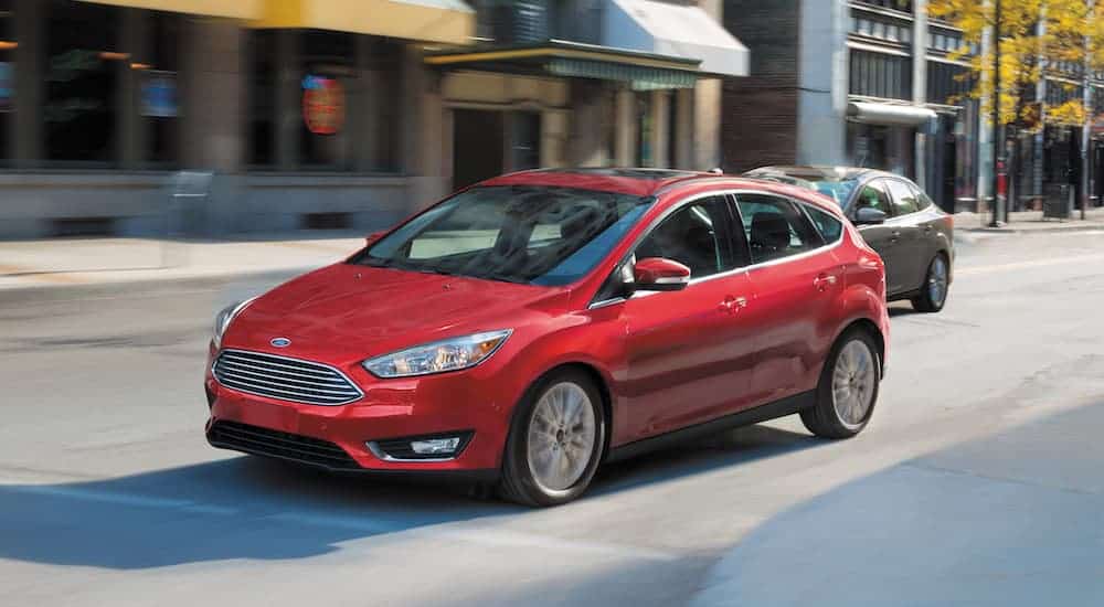 A red 2016 Ford Focus, which is popular among used cars, is driving on a city street.