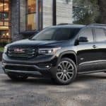 A black 2017 GMC Acadia is parked in front of a modern house.