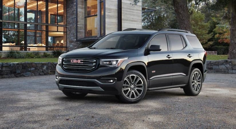 A black 2017 GMC Acadia is parked in front of a modern house.