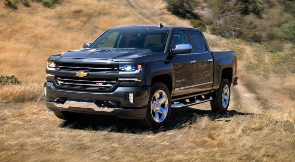 A black 2018 Chevy Silverado is driving on a trail in a field.