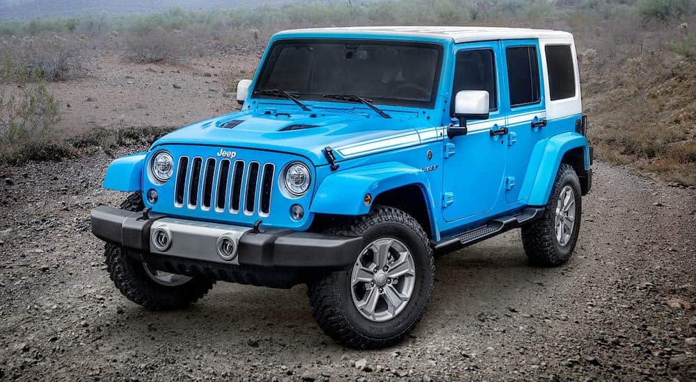 A blue 2017 Jeep Wrangler Chief is off-road on a dirt trail.