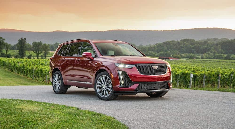 A red 2020 Cadillac XT6 Sport is parked next to a fenced in garden with mountains in the distance.