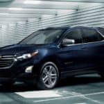 A blue 2020 Chevy Equinox, which wins when comparing the 2020 Chevy Equinox vs 2020 Ford Escape, is parked in a parking garage.