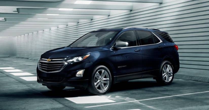 A blue 2020 Chevy Equinox, which wins when comparing the 2020 Chevy Equinox vs 2020 Ford Escape, is parked in a parking garage.