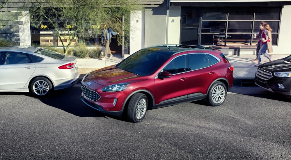 A red 2020 Ford Escape is parallel parking on a city street.