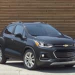 A black 2020 Chevy Trax, which wins when comparing the 2020 Chevy Trax vs 2020 Nissan Kicks, is parked in front of a brown brick wall.