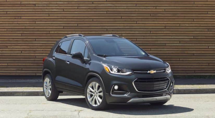 A black 2020 Chevy Trax, which wins when comparing the 2020 Chevy Trax vs 2020 Nissan Kicks, is parked in front of a brown brick wall.