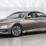 A beige 2020 Honda Accord Touring Hybrid is parked in a white showroom.