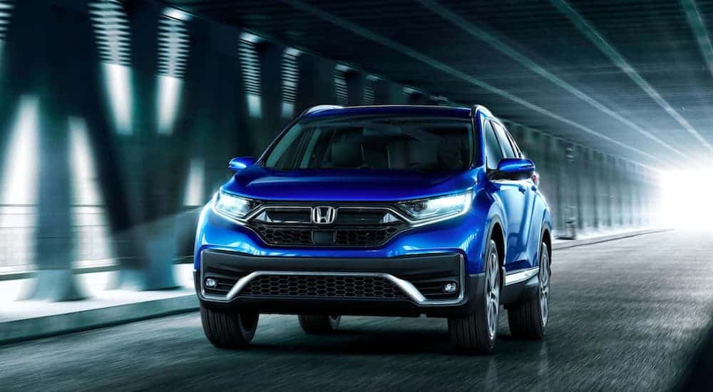 A blue 2020 Honda CR-V Touring is driving in a dark tunnel.