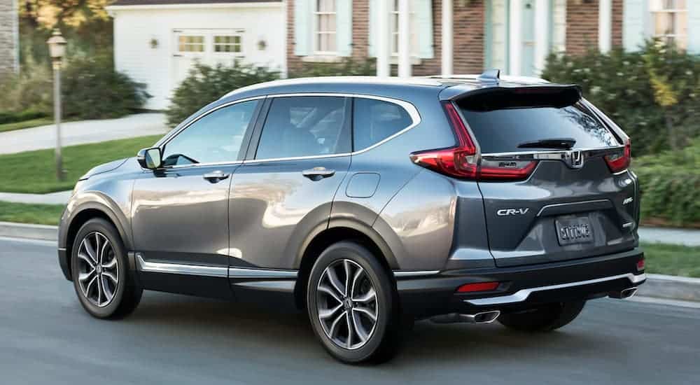 A grey 2020 Honda CR-V Touring is driving on a suburban street.