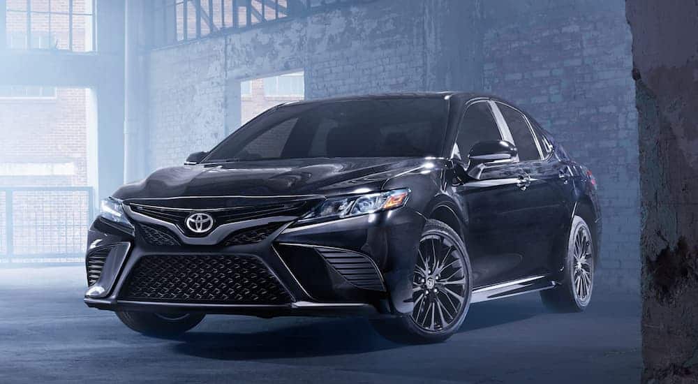 A black 2020 Toyota Camry SE is parked in a brick warehouse. 