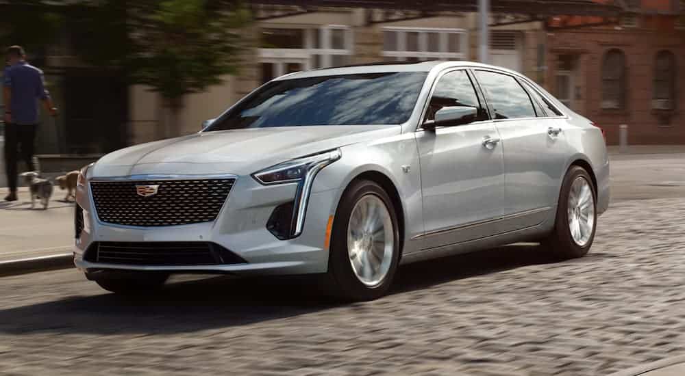 A white 2020 Cadillac CT6-V is driving on a cobble stone city street. 