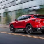 A red 2020 Chevy Blazer is driving on a city street.