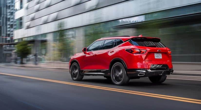 A red 2020 Chevy Blazer is driving on a city street.