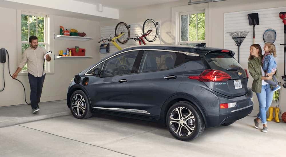 A family is in their garage with their grey 2020 Chevy Bolt EV.