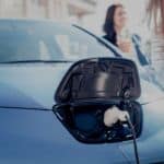 A blue electric vehicle, a popular topic in current auto news, is charging in front of two women.