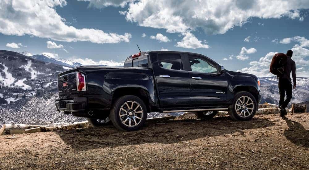 A man is walking away from his dark blue 2020 GMC Sierra 1500, which is popular among GMC trucks for sale.