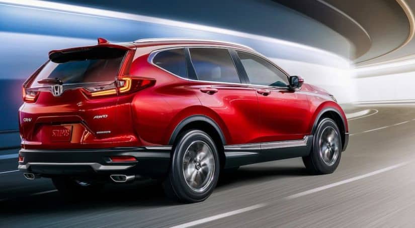 A red 2020 Honda CR-V Touring is driving through a tunnel after leaving a Honda dealer.
