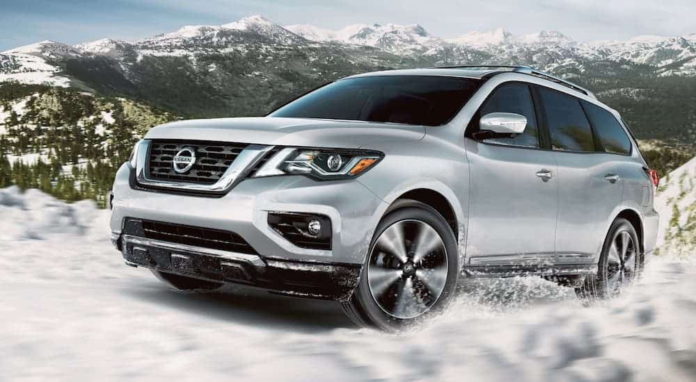 A silver 2020 Nissan Pathfinder is driving in the snow.