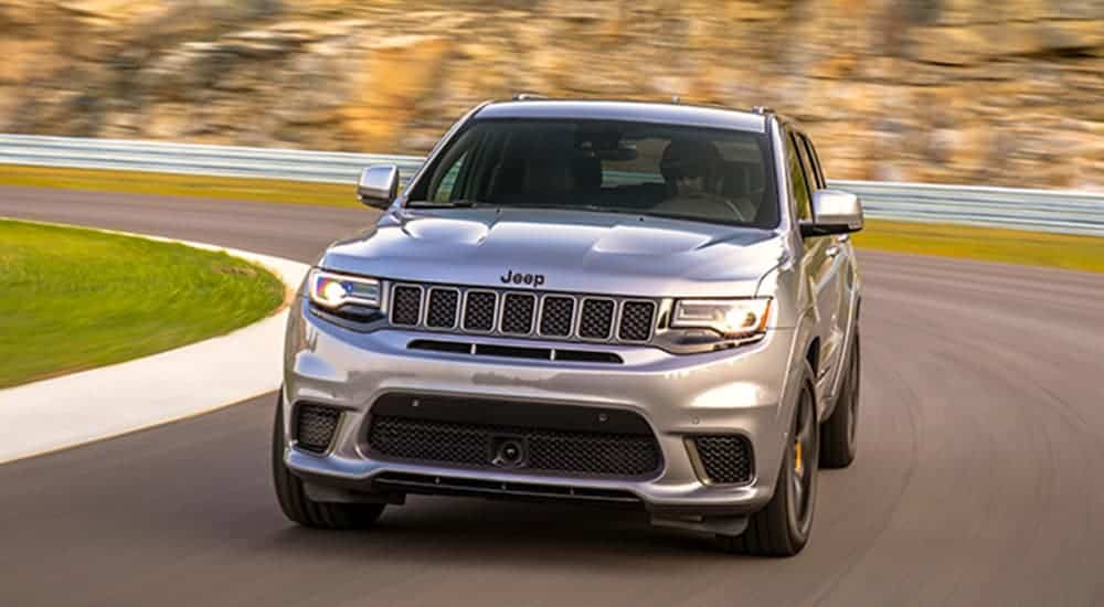 A silver 2020 Jeep Grand Cherokee Trackhawk is driving around a corner.