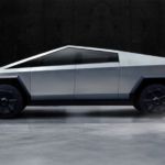 A silver Tesla Cybertruck is shown from the side in a dark room.