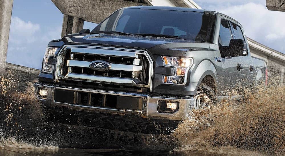 A grey 2017 Ford F-150 is driving through muddy water.