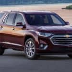 A burgundy 2018 used Chevy Traverse is parked in front of a lake at sunset.