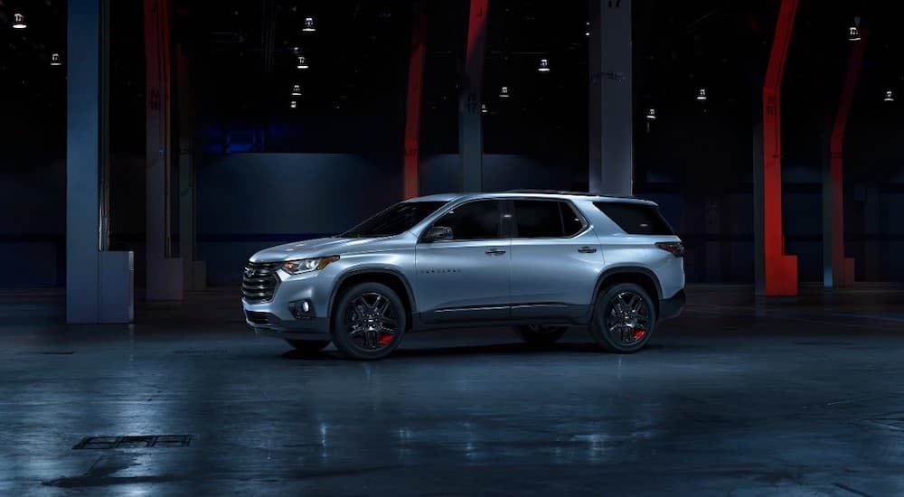 A silver 2018 used Chevy Traverse Redline edition is parked in a dark room.