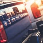 A row of used trucks is shown with a sun glare.