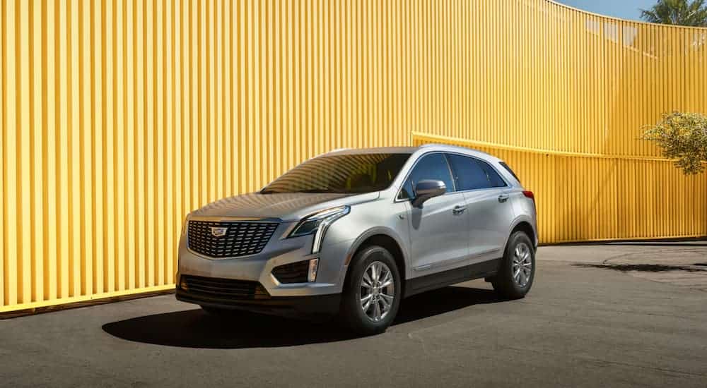 A grey 2020 Cadillac XT5 is parked in front of a yellow wall.