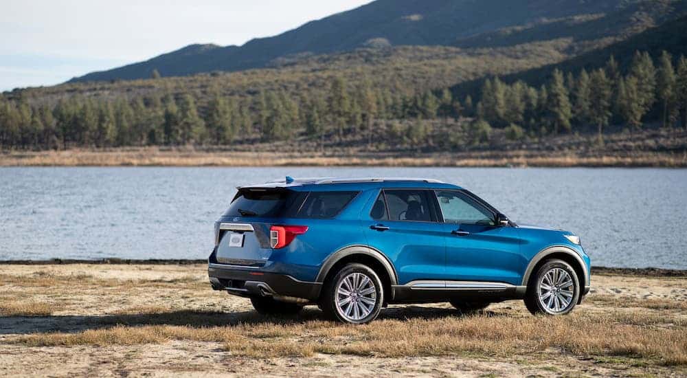 A blue 2020 Ford Explorer Hybrid is parked next to a lake.