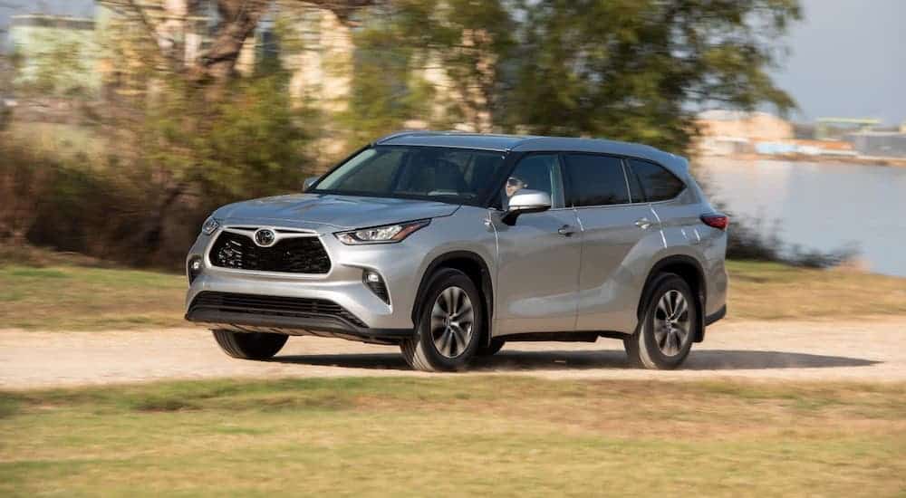 A silver 2020 Toyota Highlander XLE is driving away from a lake.